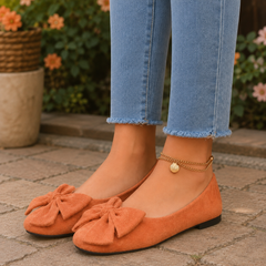 Ballerine arancioni con maxi fiocco sul davanti e punta tonda, indossate con pantaloni chiari