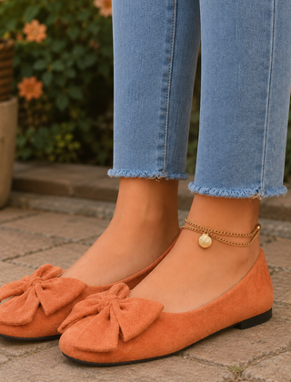 Ballerine arancioni con maxi fiocco sul davanti e punta tonda, indossate con pantaloni chiari