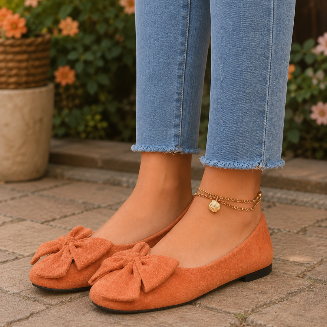 Ballerine arancioni con maxi fiocco sul davanti e punta tonda, indossate con pantaloni chiari