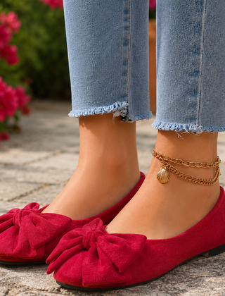 Ballerine rosse con fiocco voluminoso davanti, abbinate a pantaloni chiari sfrangiati