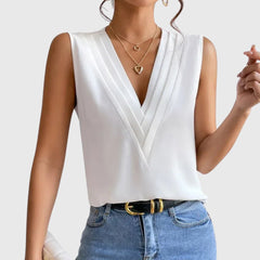 Camicetta bianca senza maniche con scollo a V incrociato e pantalone chiaro a vita alta