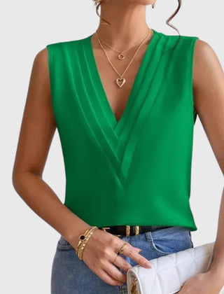 Camicetta verde senza maniche dal profondo scollo a V, abbinata a bracciali dorati