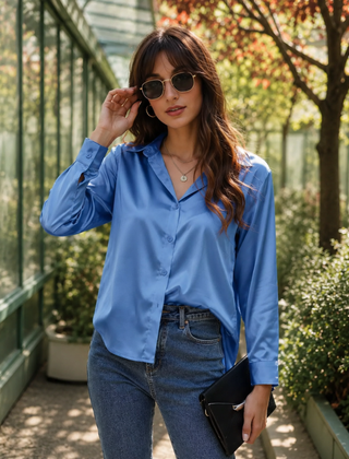 Camicia blu chiaro con chiusura a bottoni e polsini, abbinata a pantaloni grigi