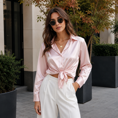 Camicia rosa lucida annodata in vita abbinata a pantaloni bianchi ampi