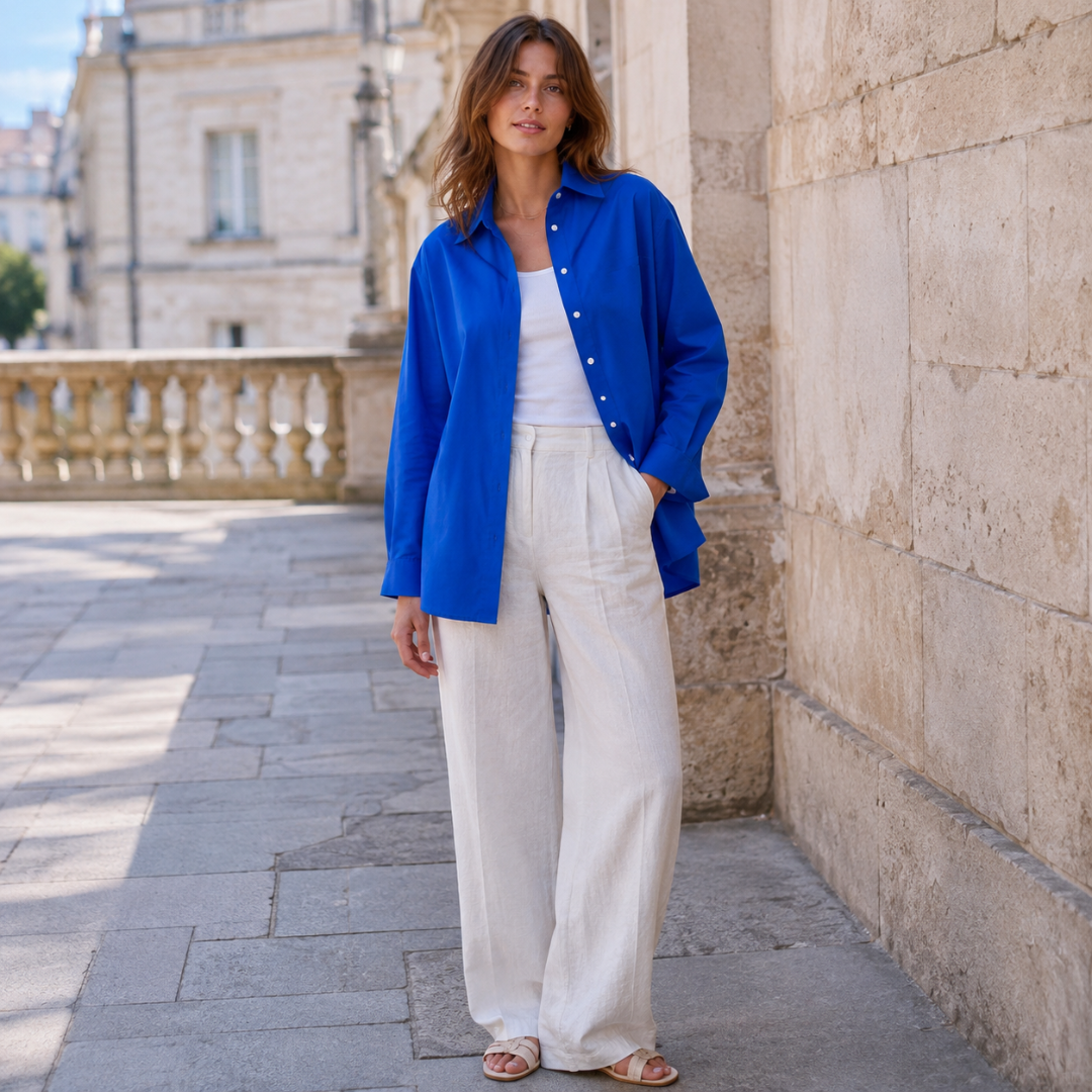 Camicia blu donna aperta con colletto classico, indossata su pantaloni larghi color crema