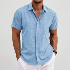 Camicia uomo azzurra maniche corte, look estivo con pantaloni bianchi e polsini risvoltati