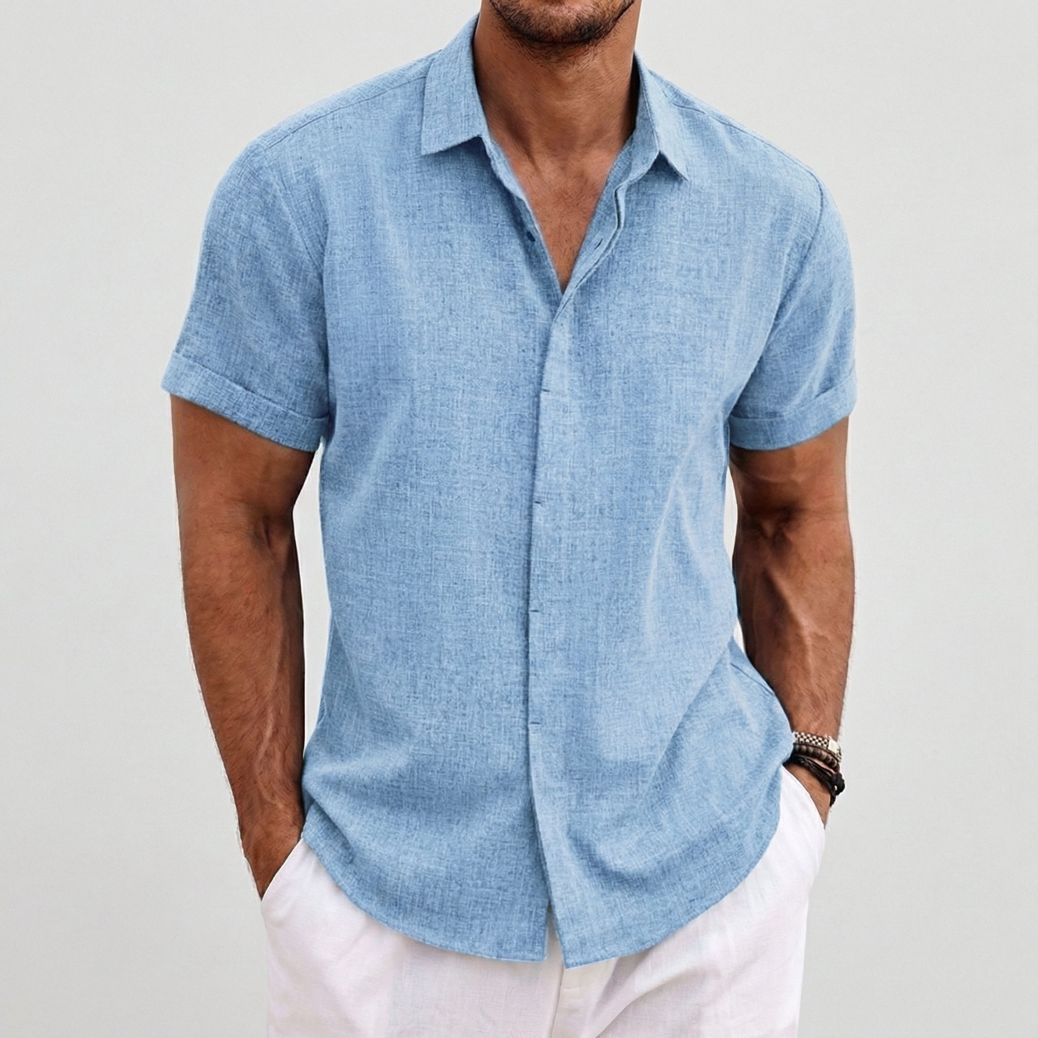 Camicia uomo azzurra maniche corte, look estivo con pantaloni bianchi e polsini risvoltati