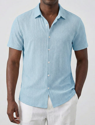 Camicia uomo celeste maniche corte dalla superficie rigata, indossata con pantaloni bianchi