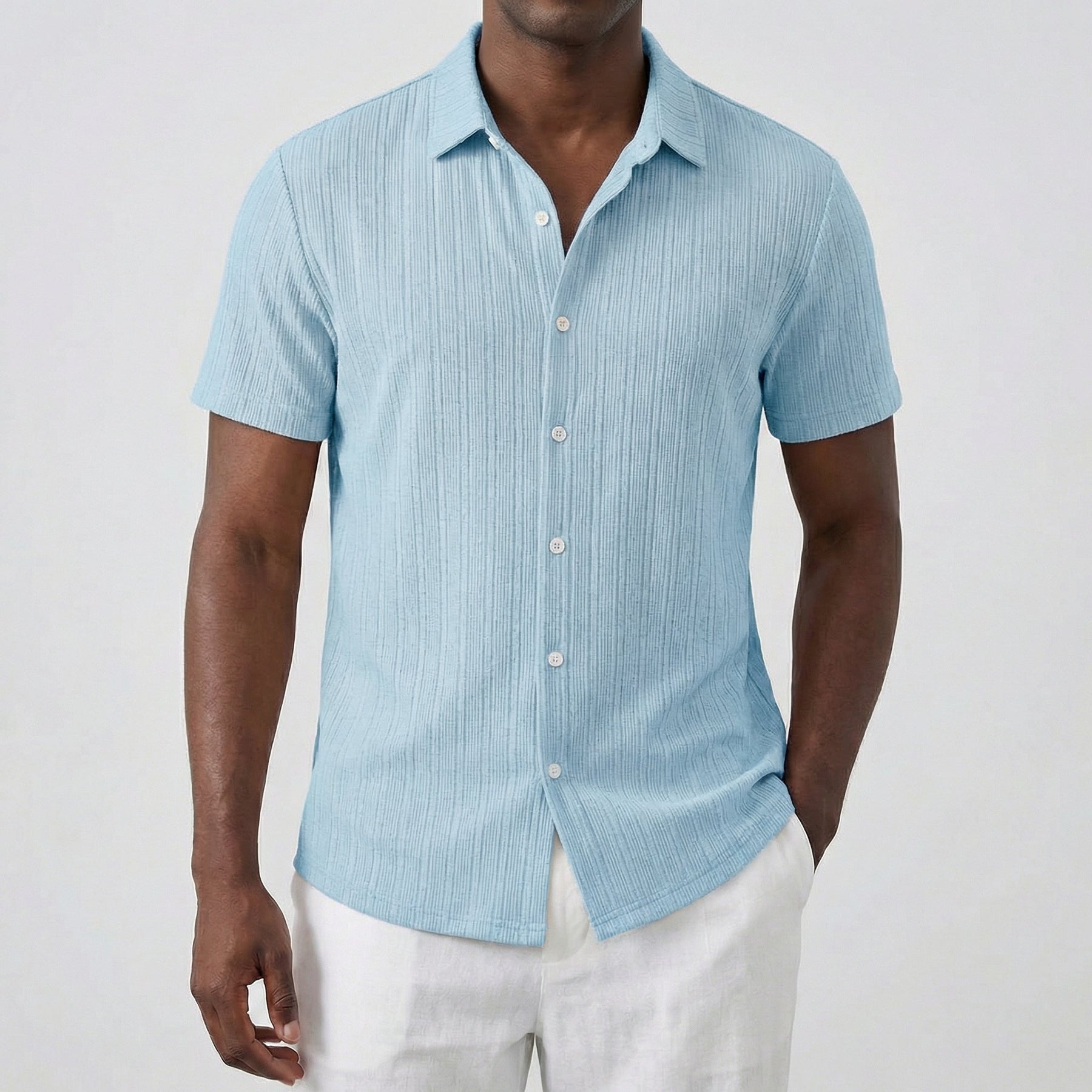 Camicia uomo celeste maniche corte dalla superficie rigata, indossata con pantaloni bianchi