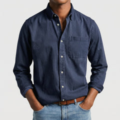 Camicia uomo blu navy con bottoni chiari e polsini arrotolati, look casual
