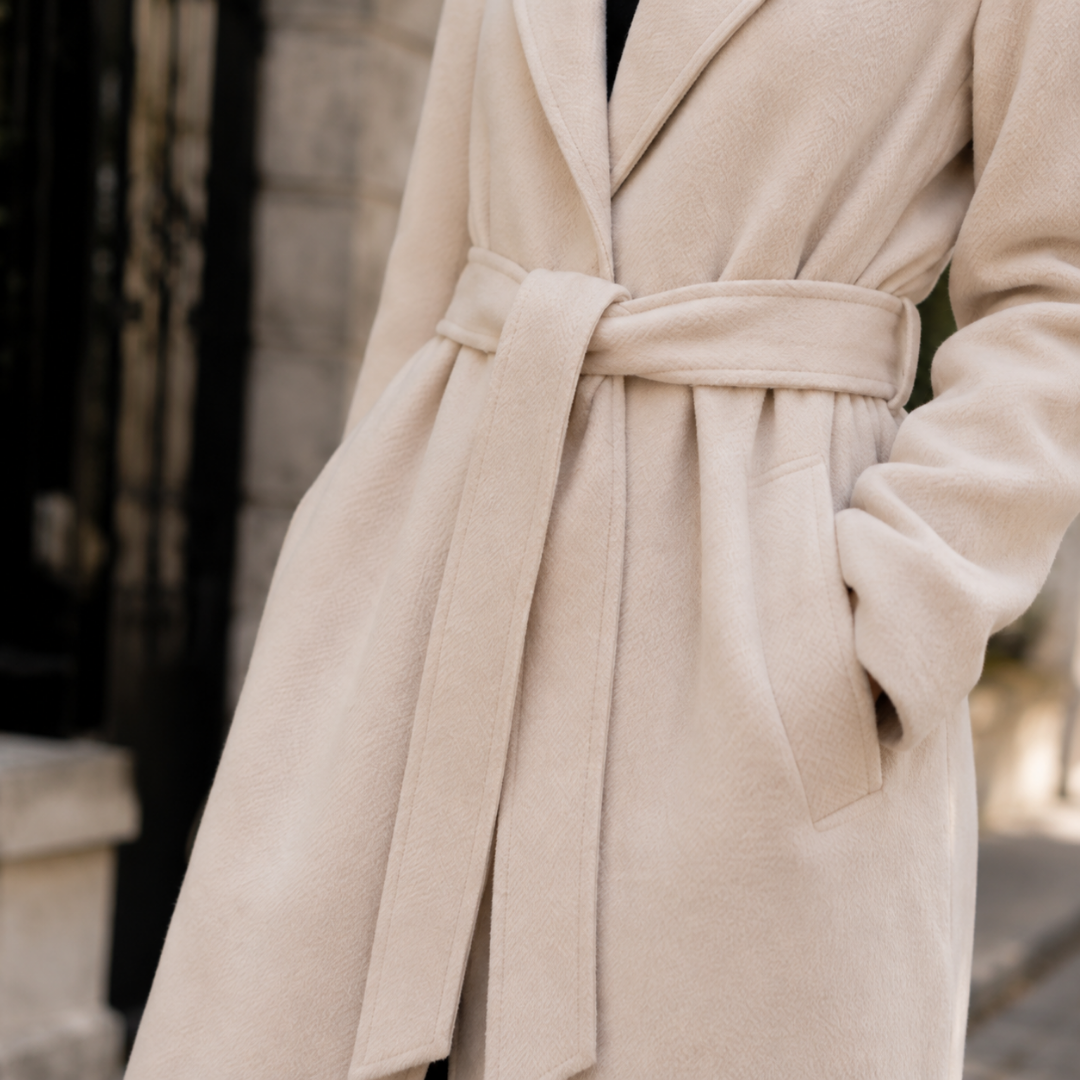 Primo piano della cintura annodata e della tasca laterale del cappotto beige