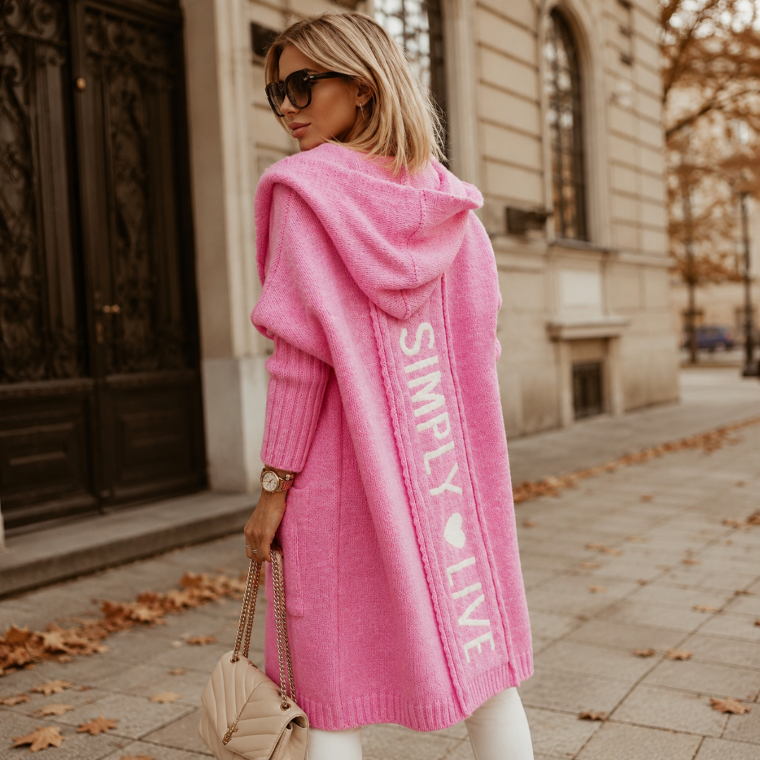 Retro del cardigan rosa con cappuccio e scritta bianca verticale lungo la schiena