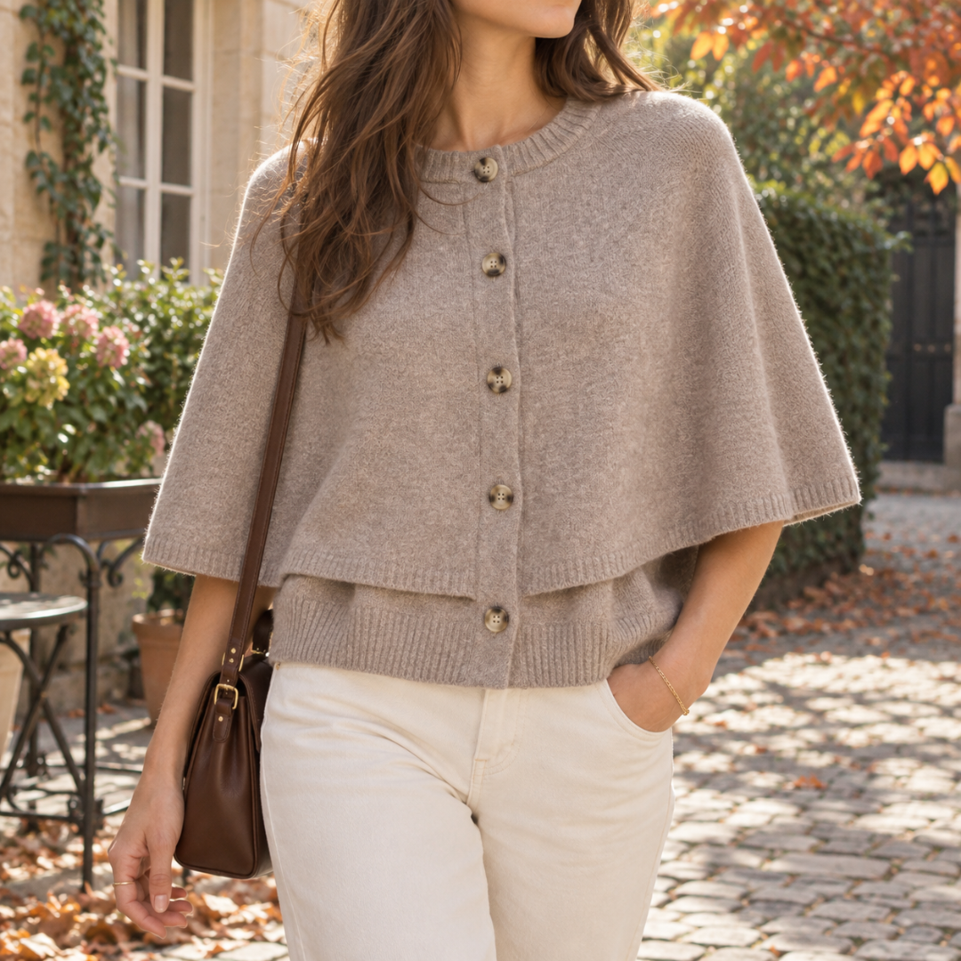 Cardigan beige corto con mantellina e cinque bottoni frontali su pantaloni crema