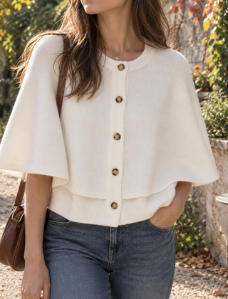 Cardigan bianco a mantella con bottoni scuri e girocollo a coste su pantaloni blu