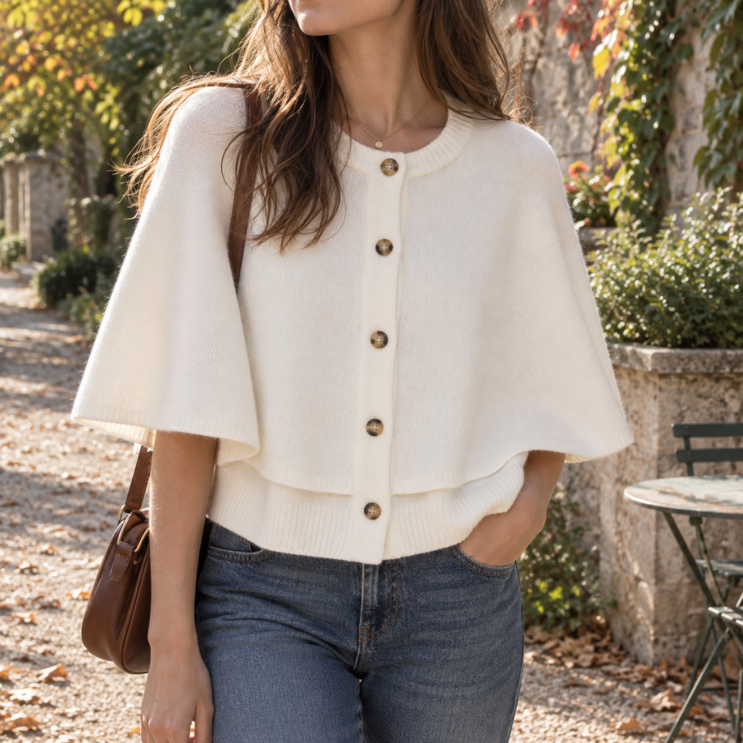 Cardigan bianco a mantella con bottoni scuri e girocollo a coste su pantaloni blu
