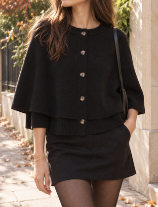 Cardigan nero a mantella con bottoni frontali indossato con minigonna nera e collant