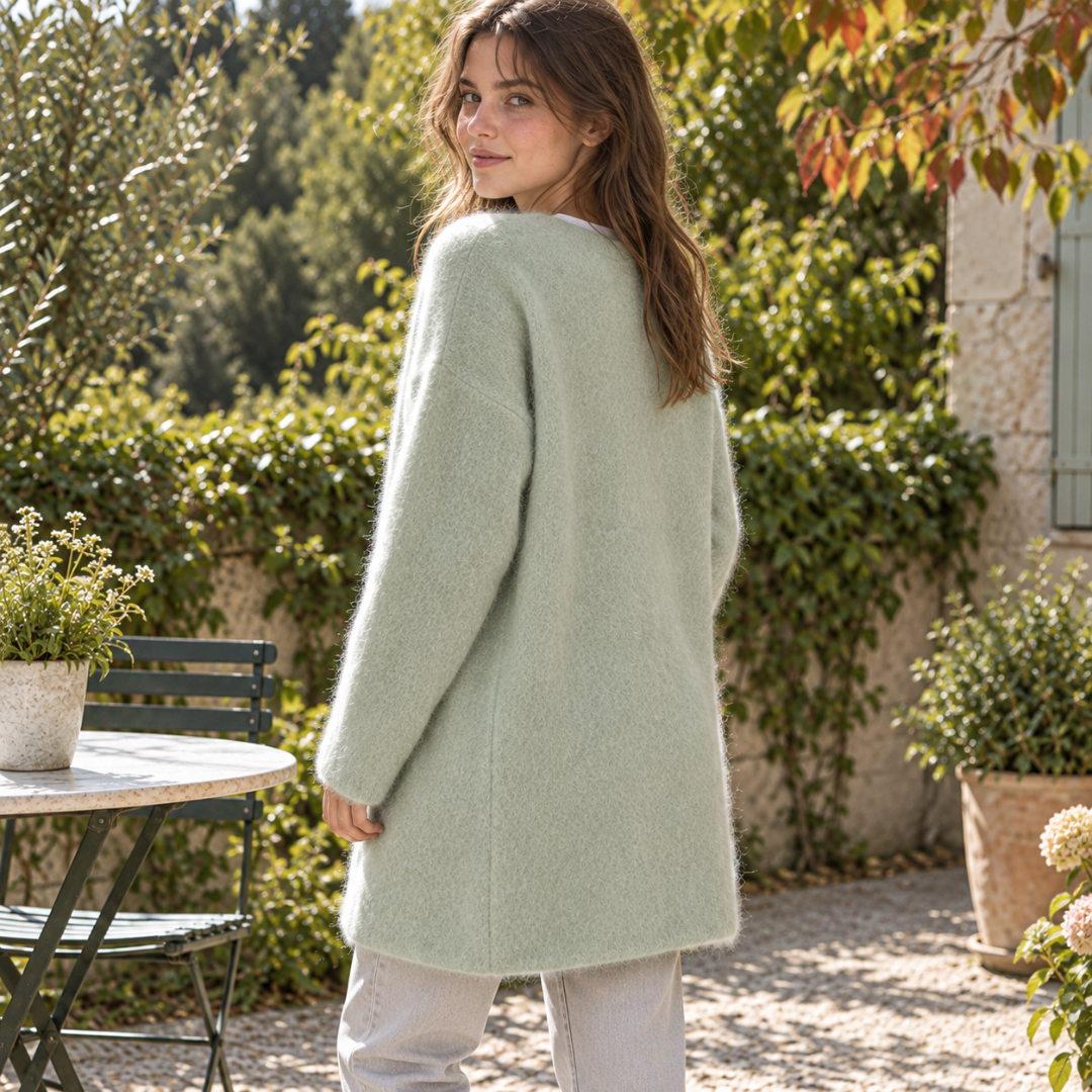 Cardigan verde visto di spalle, maglia vaporosa e linea lunga oltre il fianco