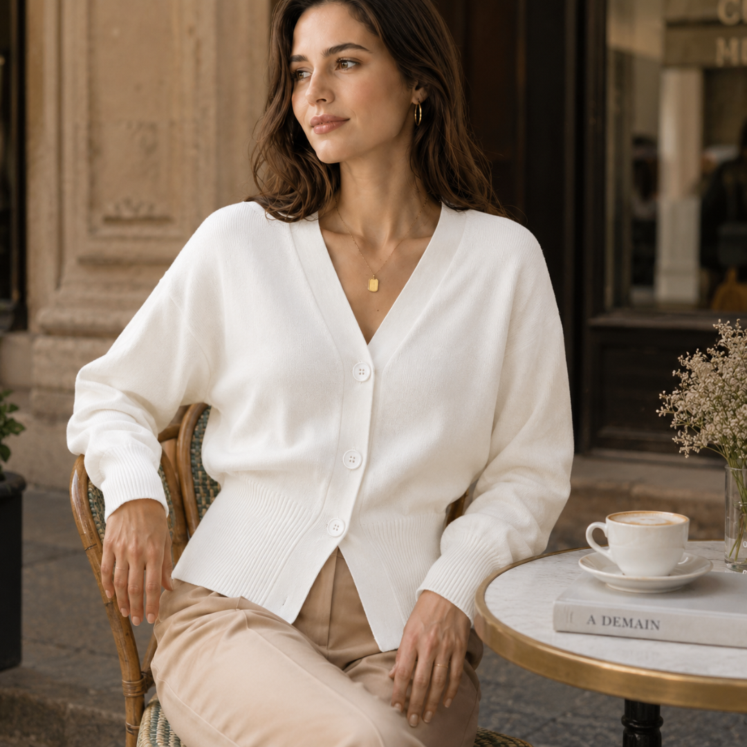 Donna seduta al caffè con cardigan bianco a scollo a V e bottoni
