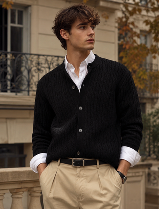 Cardigan uomo nero in maglia intrecciata con bottoni, su camicia bianca e pantaloni chiari