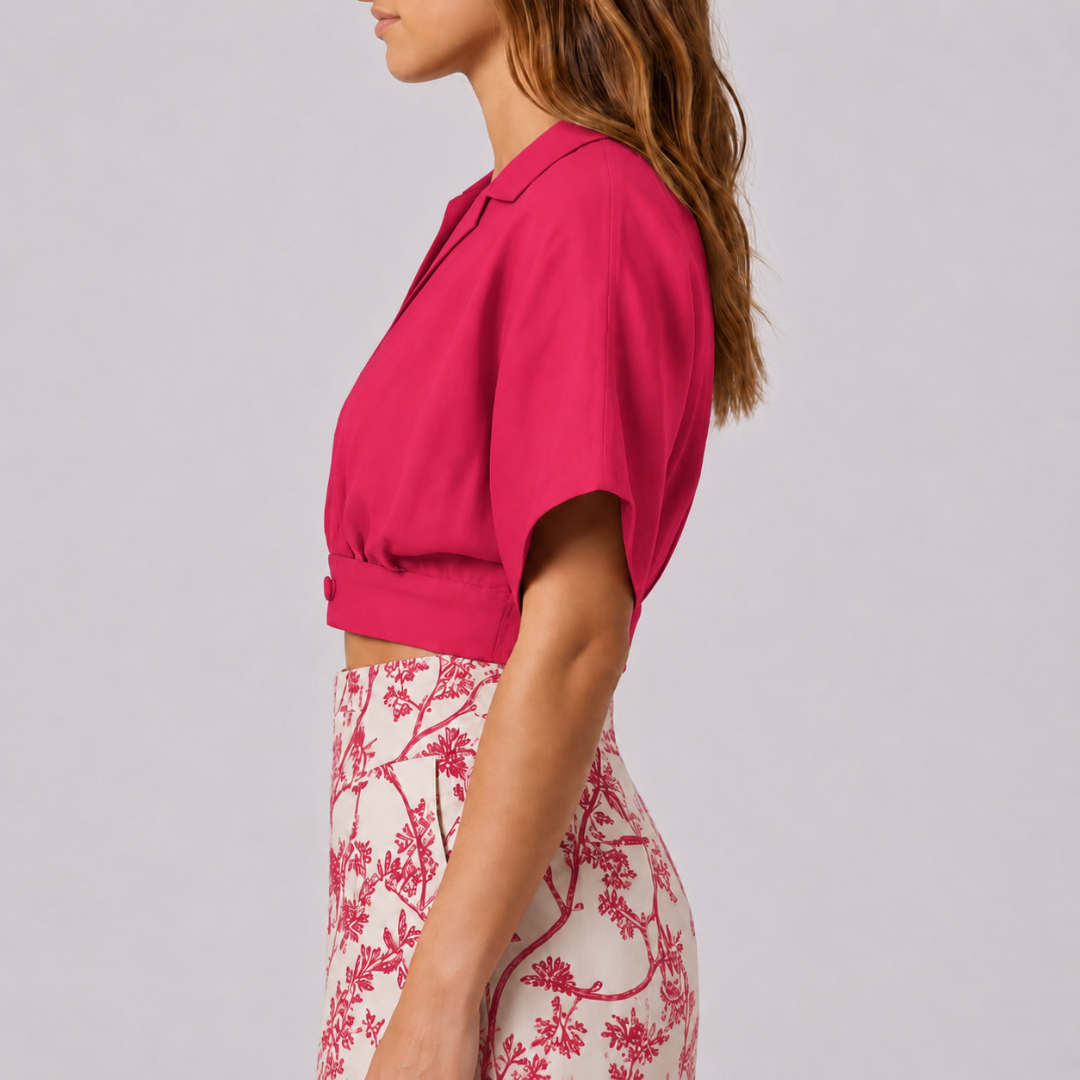 Profilo del crop top fucsia con maniche corte a kimono e bottone laterale in vita