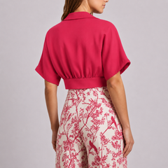 Vista posteriore del completo fucsia con pantaloni chiari a stampa di rami e uccellini