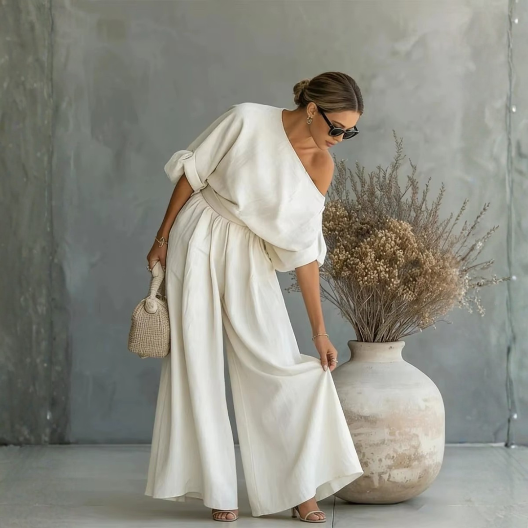 Donna mostra l'ampiezza dei pantaloni palazzo bianchi abbinati al top asimmetrico morbido