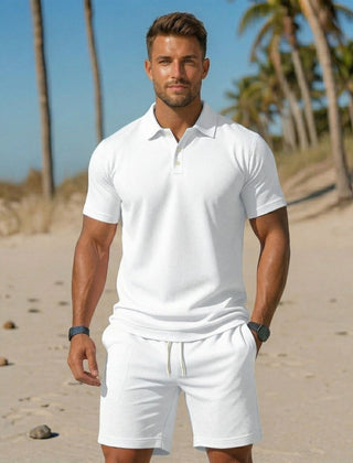 Completo uomo bianco con polo manica corta e shorts con coulisse sulla sabbia