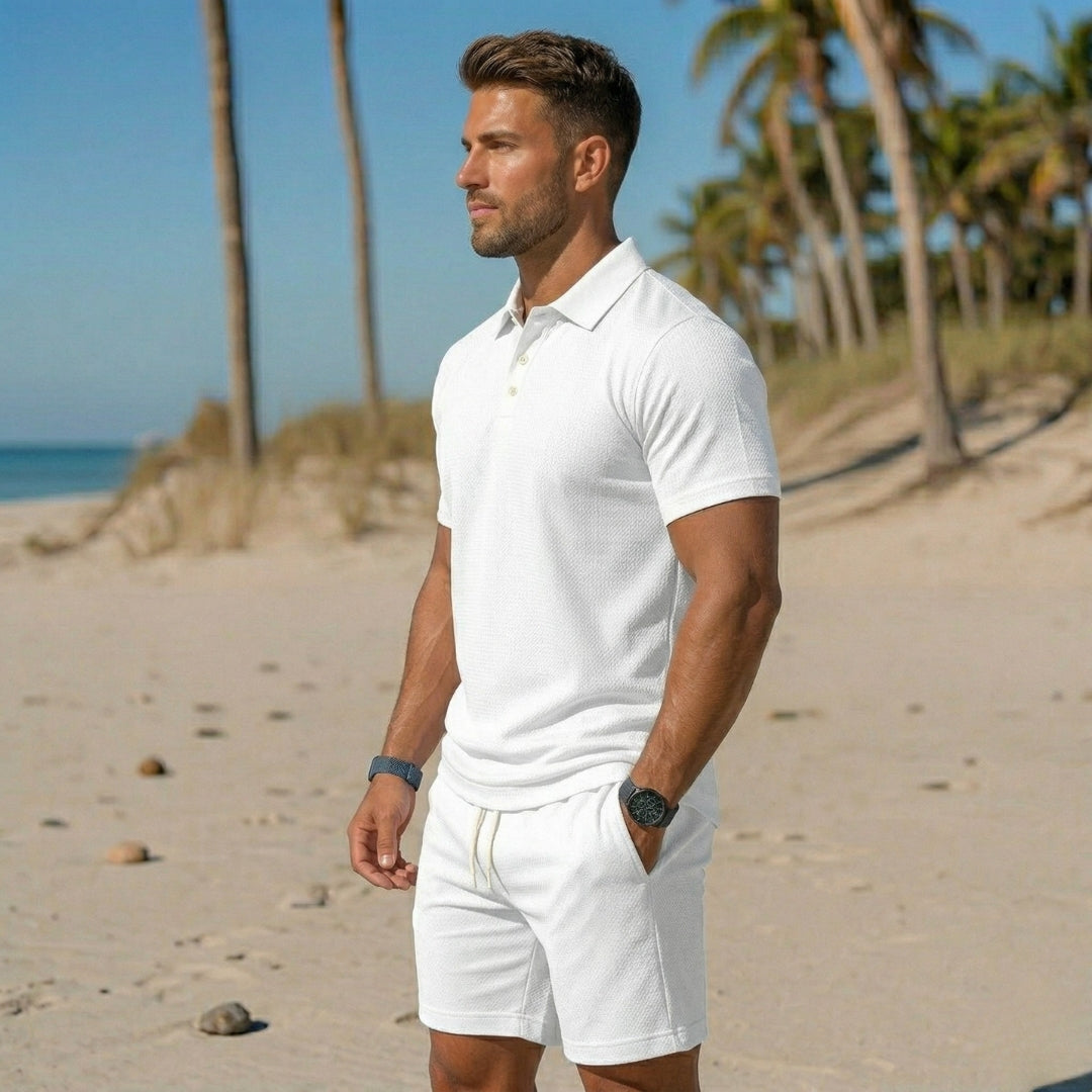 Polo bianca con colletto aperto e shorts bianchi corti indossati in spiaggia