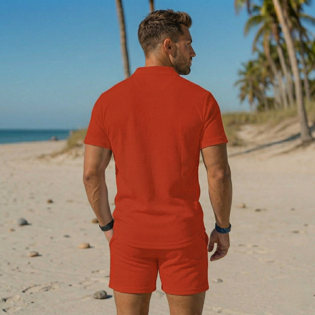 Retro del completo uomo rosso, polo dritta sui fianchi e shorts sopra il ginocchio