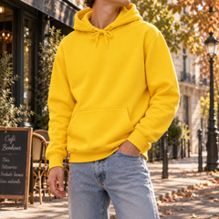 Felpa gialla con cappuccio indossata con pantaloni chiari, tasca frontale in evidenza
