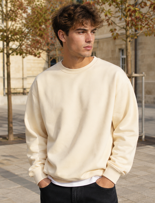 Felpa uomo beige a girocollo abbinata a pantaloni neri in contesto urbano