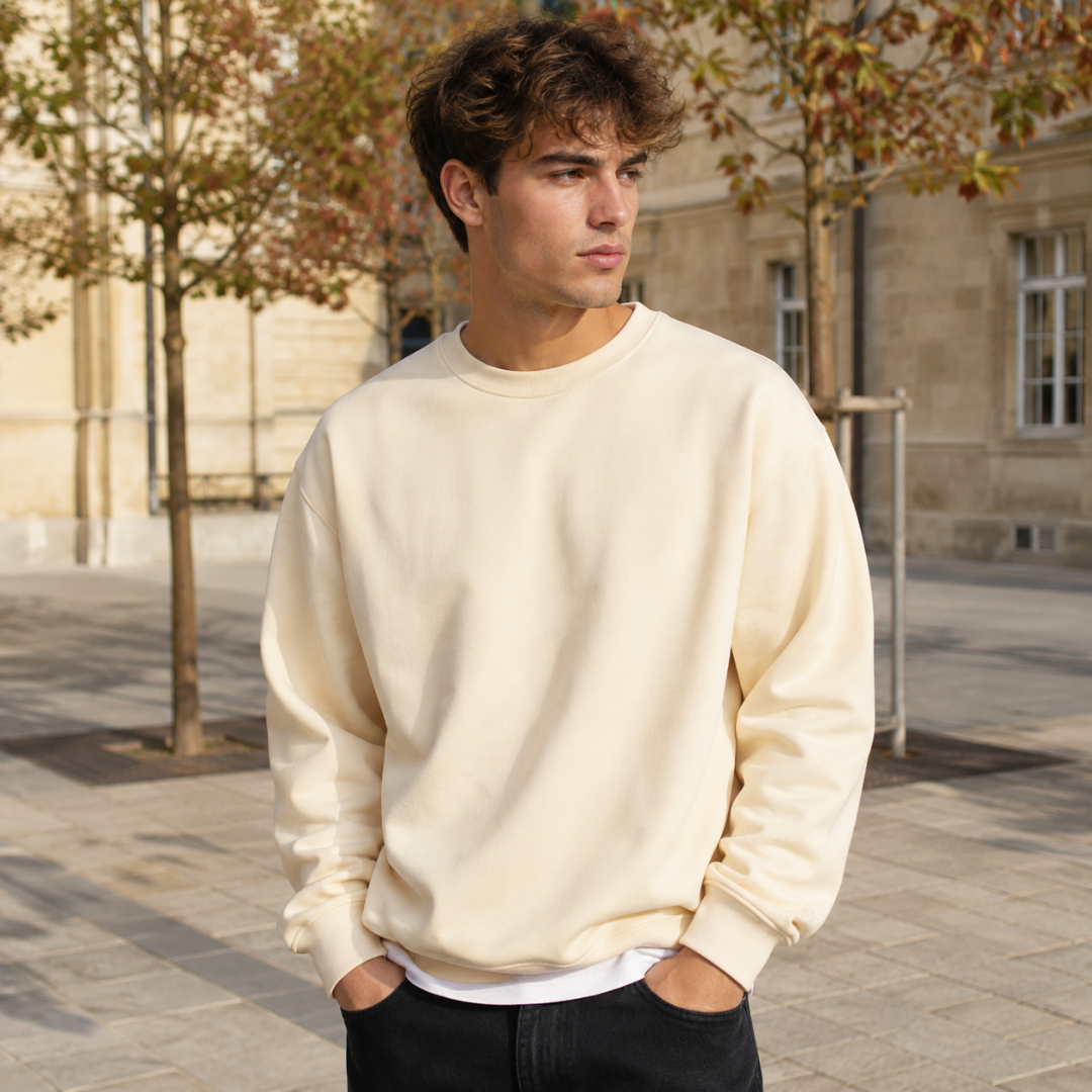 Felpa uomo beige a girocollo abbinata a pantaloni neri in contesto urbano