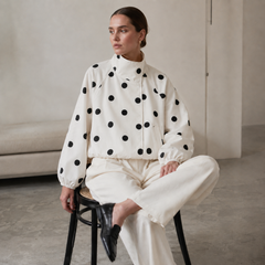 Donna seduta con giacca a pois beige, maniche raglan e polsini arricciati