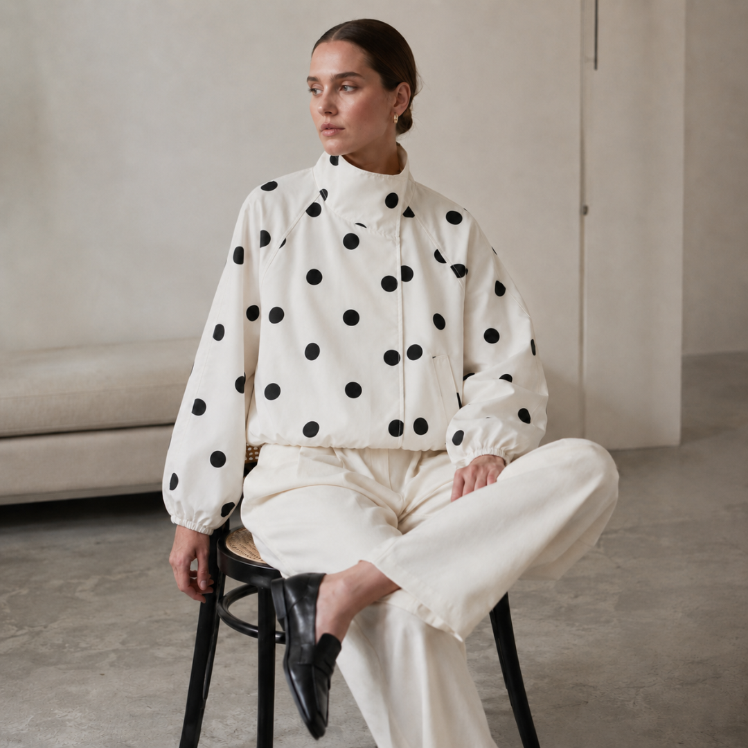 Donna seduta con giacca a pois beige, maniche raglan e polsini arricciati