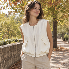 Gilet donna bianco smanicato con zip frontale e fondo arricciato, su pantaloni beige