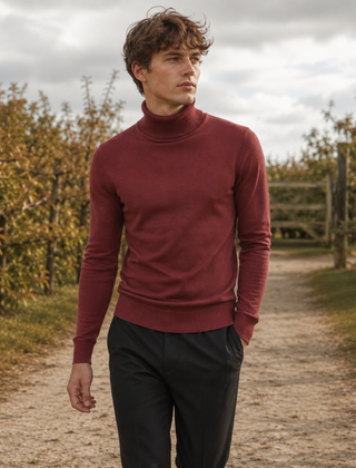 Uomo con maglione dolcevita rosso e pantaloni neri su un sentiero di campagna