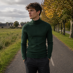 Maglione dolcevita verde scuro da uomo con collo alto lungo una strada alberata
