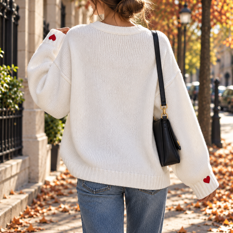 Vista posteriore del maglione bianco con spalle scese e cuori ricamati sui polsini