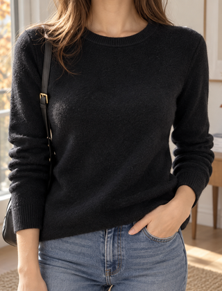 Maglione donna nero a girocollo indossato con pantaloni chiari e borsa nera