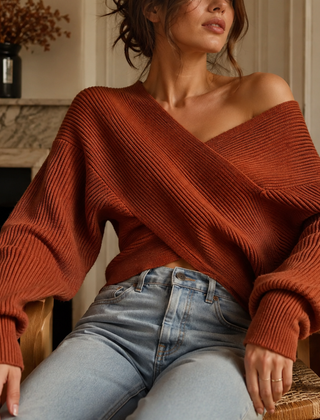 Maglione rosso arancio a coste con scollo ampio su una spalla