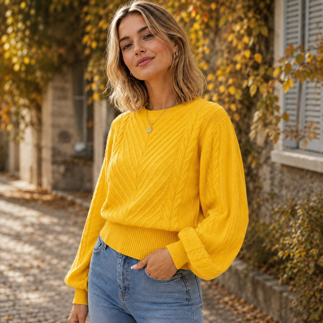 Dettaglio del maglione giallo con motivo a spina sul davanti e polsini a coste