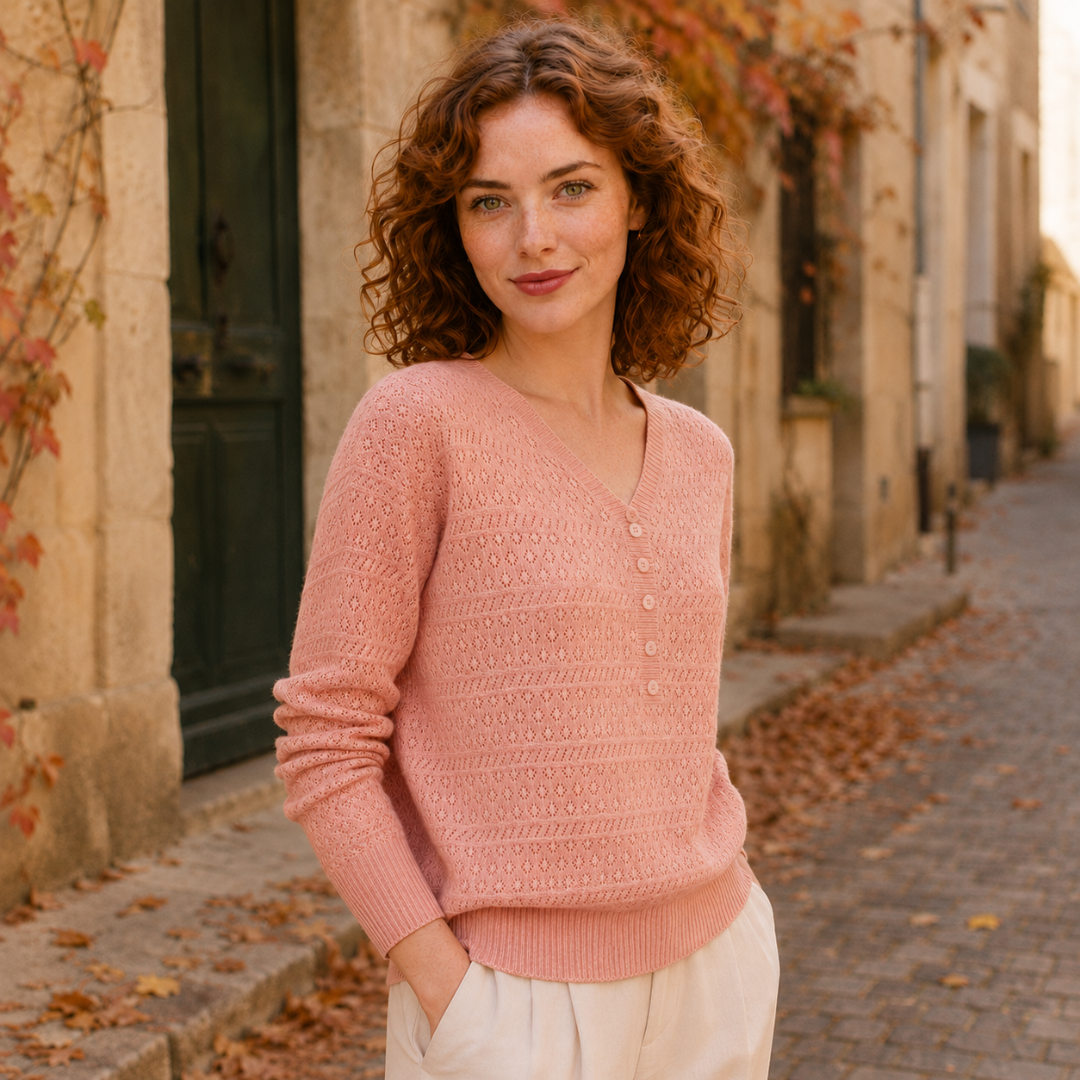 Maglione rosa traforato visto di tre quarti con abbottonatura centrale e fondo a coste
