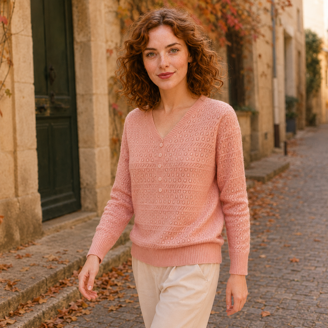 Maglione rosa traforato indossato con pantaloni chiari, scollo a V ben visibile