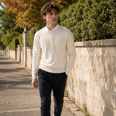 Uomo cammina indossando maglione crema a girocollo e pantaloni blu navy