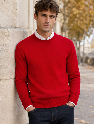 Maglione uomo rosso scarlatto a girocollo con maniche lunghe, appoggiato a un muro