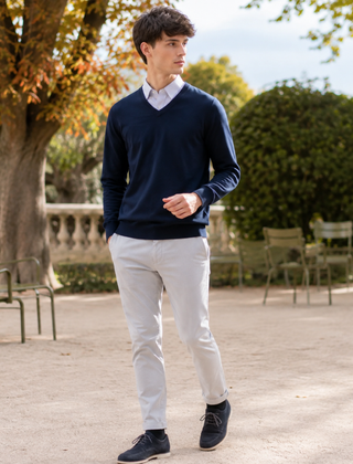Maglione uomo blu scuro con scollo a V, camicia a righe e pantaloni chiari
