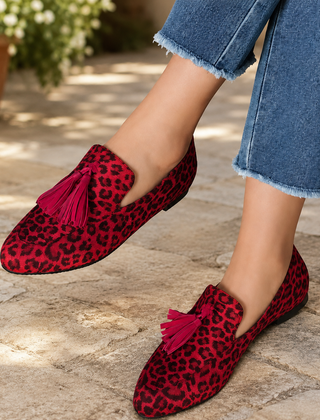 Mocassini animalier rossi con nappine a contrasto, indossati con pantaloni sfrangiati