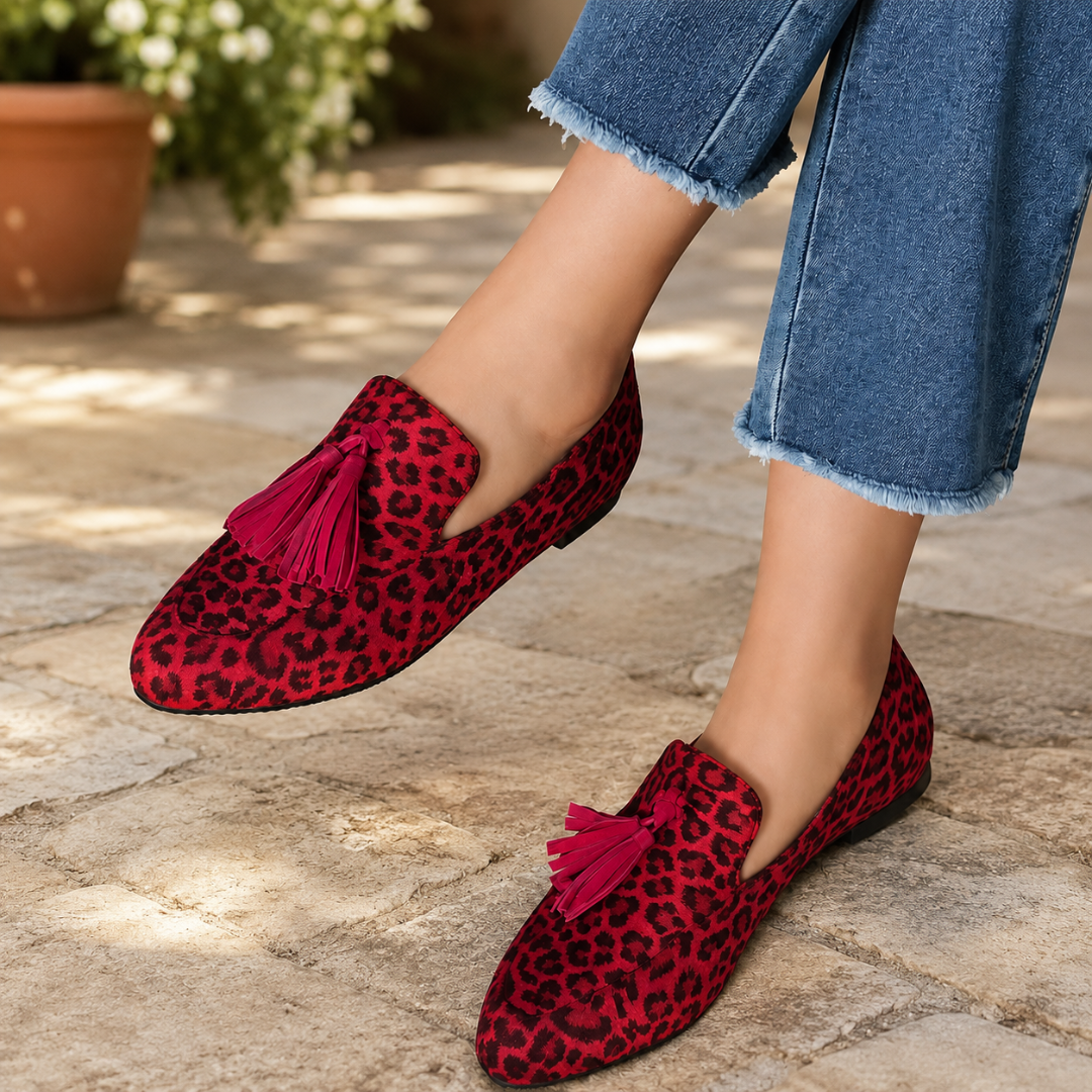Mocassini animalier rossi con nappine a contrasto, indossati con pantaloni sfrangiati