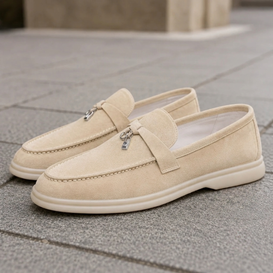 Mocassini beige slip on con pendente metallico e suola chiara su pavimentazione urbana