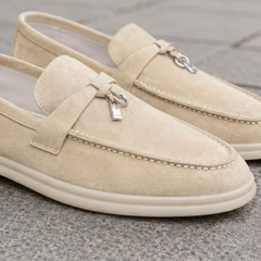 Dettaglio ravvicinato dei mocassini beige con cuciture a vista e ciondolo metallico